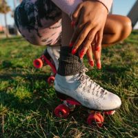 Close-up of a woman enjoying leisure time on roller skates in a sunny park setting.